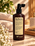 Brown 200 ml bottle of maad Big Booster Volumax Leave-In with applicator beside towels and hairbrush